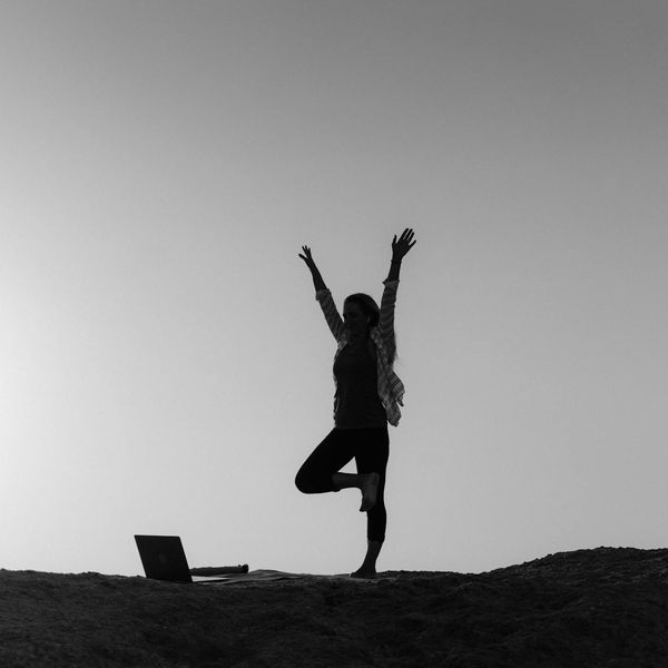 Silhouette of a person in a yoga pose against a vibrant sunrise.